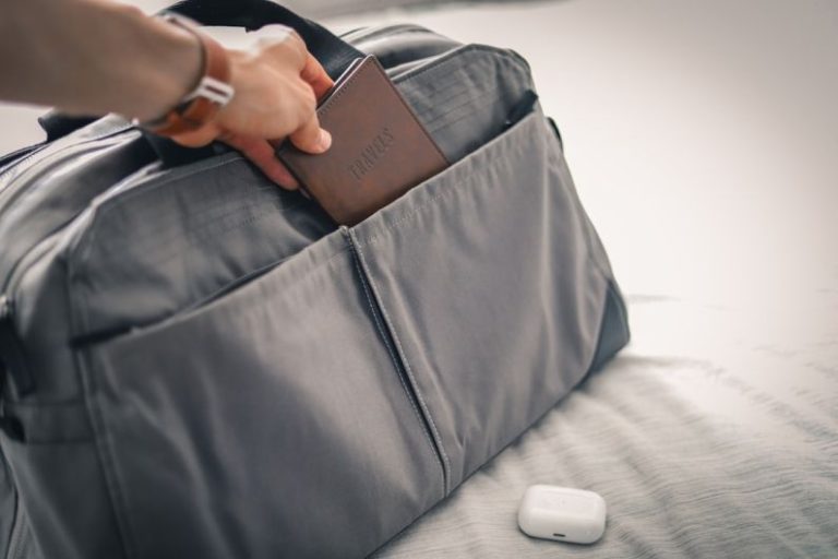 Bag - a person holding a wallet in a bag on a bed