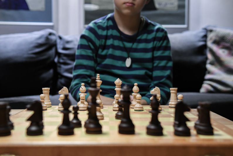 Key Pieces - boy in green and black striped sweater playing chess