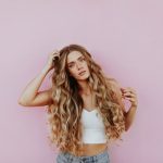 Hairstyles - woman standing next to pink wall while scratching her head