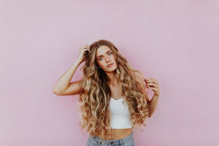Hairstyles - woman standing next to pink wall while scratching her head